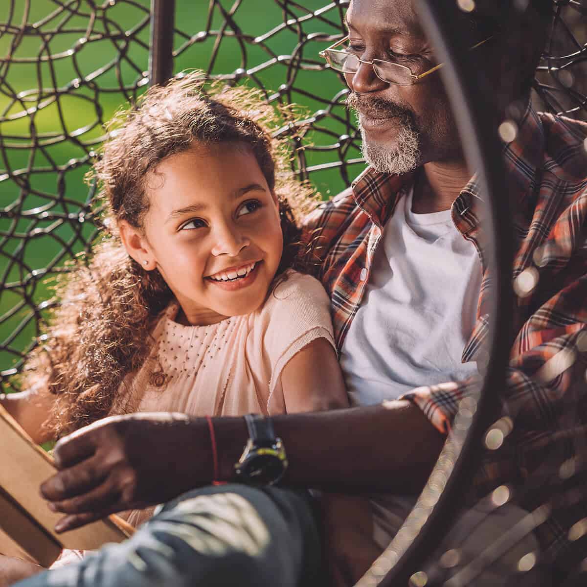 African American grand father and grand daughter reading a book and smiling