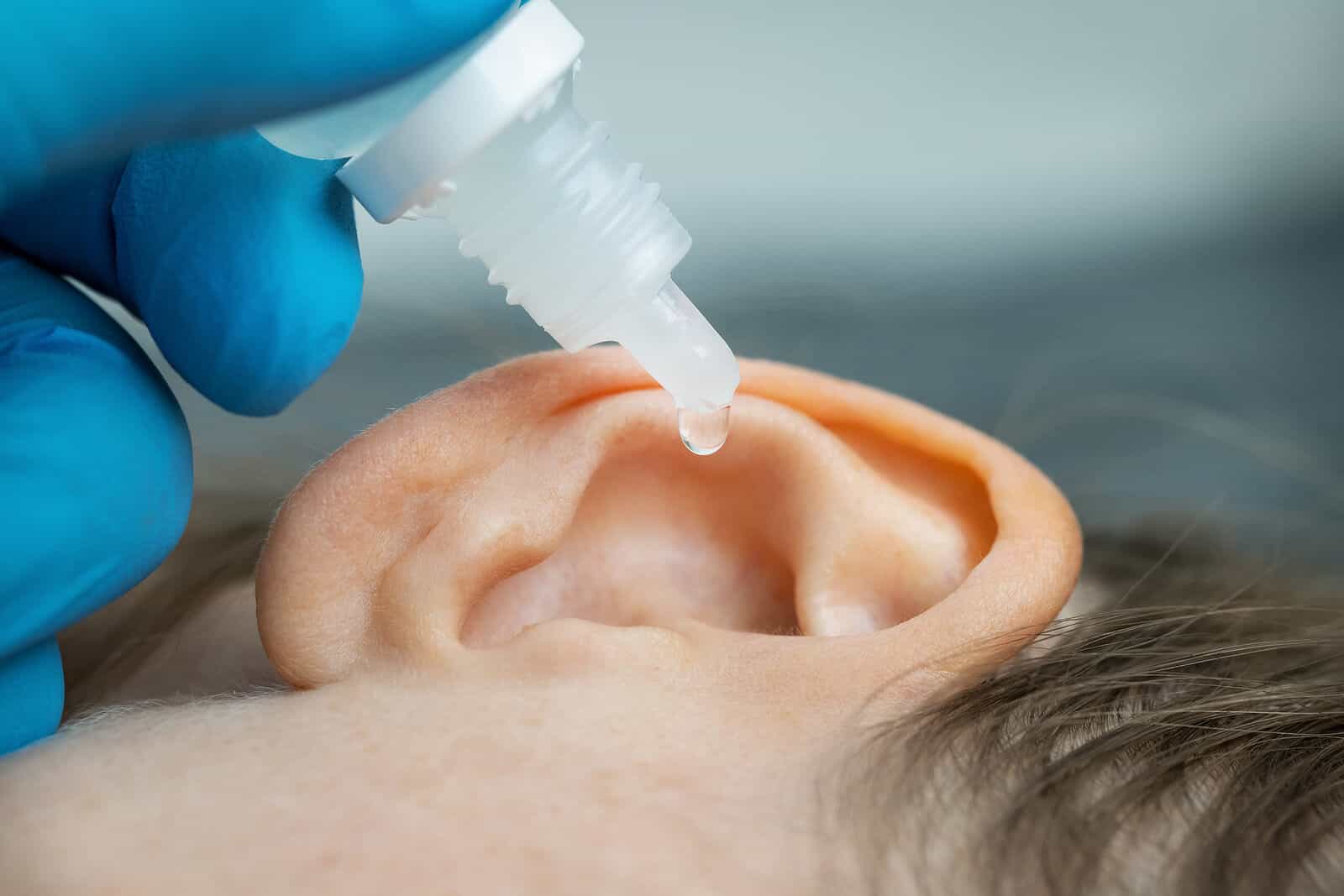 Doctor dripping ear drops into patients ear